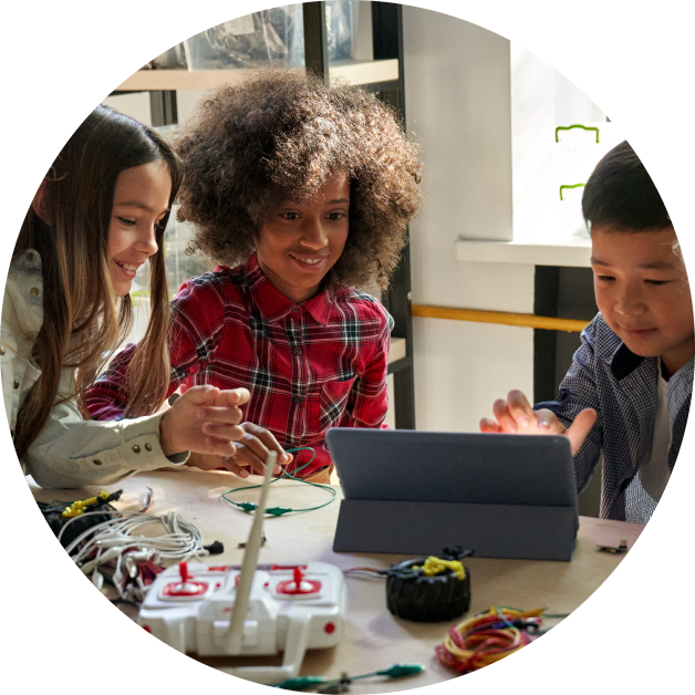 group of three children smiling, working on tablet