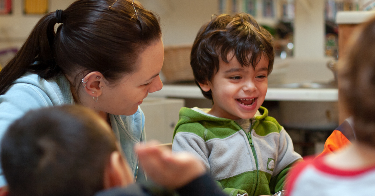 smiling child with other children and one adult