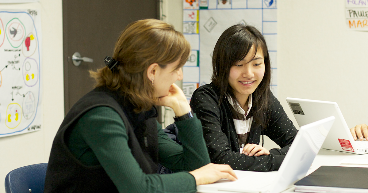 Teacher with student on laptop