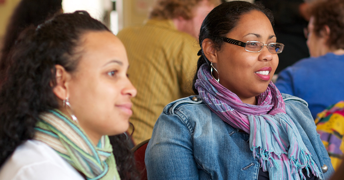 Two african american women participating in a group discussion