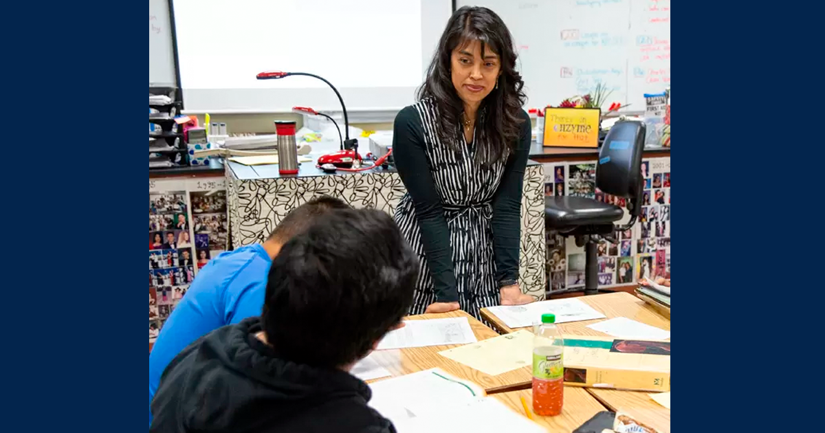 Photo of teacher at a classroom desk