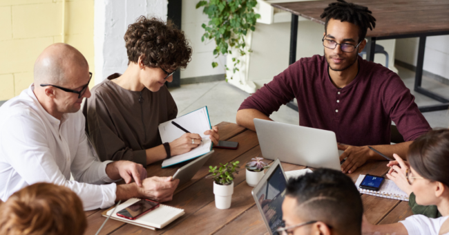 A group of professionals working together on their laptops at a table.