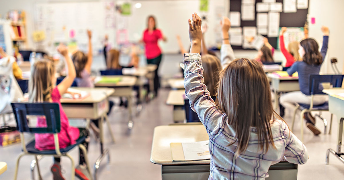 Students with hands raised in a classroom